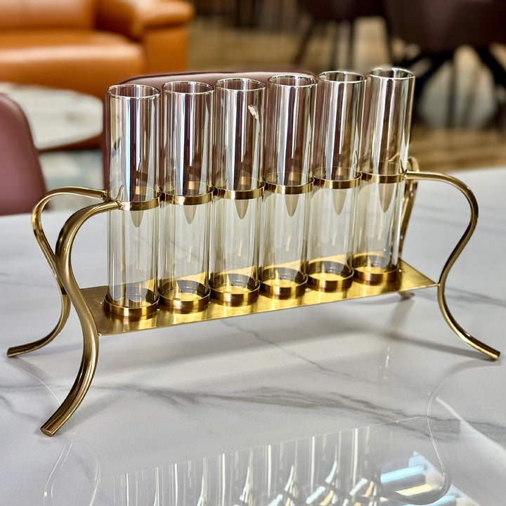 Set of clear glass vials with gold metal holder on a marble surface