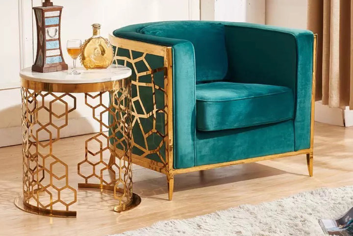 Teal velvet armchair with gold geometric legs next to a matching side table in a room.