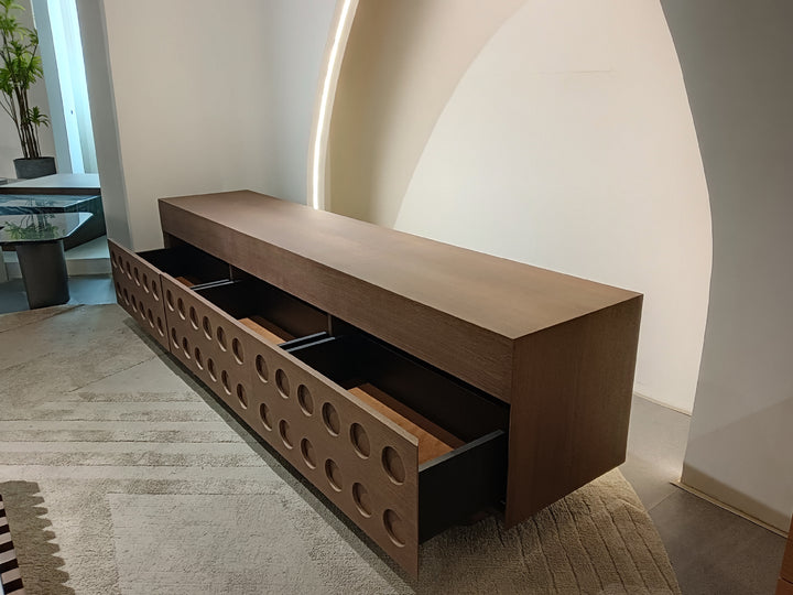 Modern wooden cabinet with perforated design in a minimalistic room.