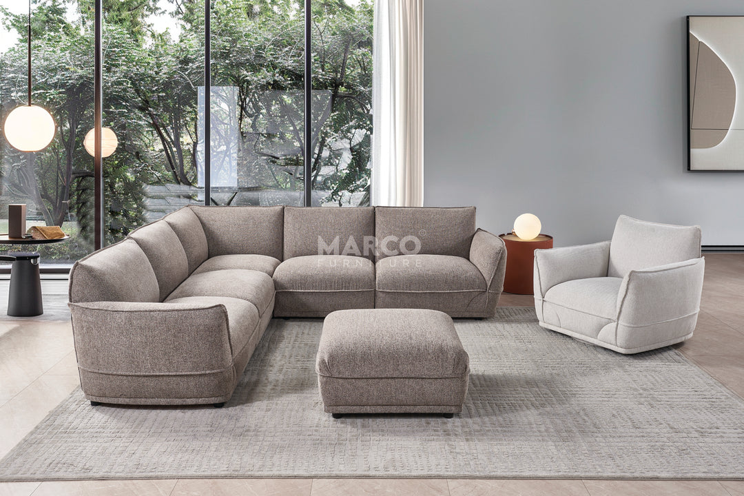 Gray sectional sofa with matching ottoman and armchair in a modern living room setting.
