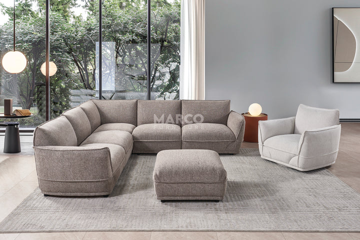 Gray sectional sofa with matching ottoman and armchair in a modern living room setting.