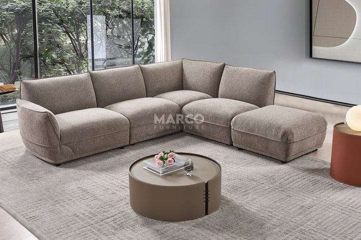Gray sectional sofa in a modern living room with 'Marco Furniture' branding.