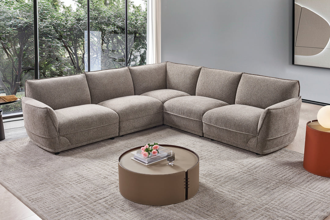 Gray sectional sofa in a modern living room with a round coffee table.