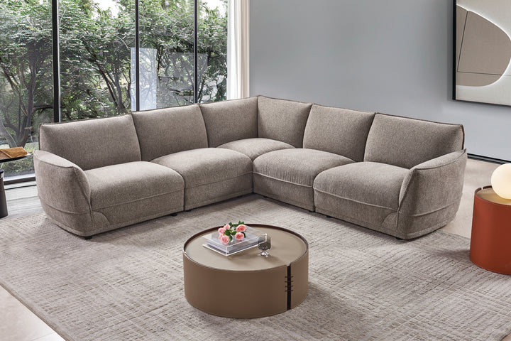 Gray sectional sofa in a modern living room with a round coffee table.