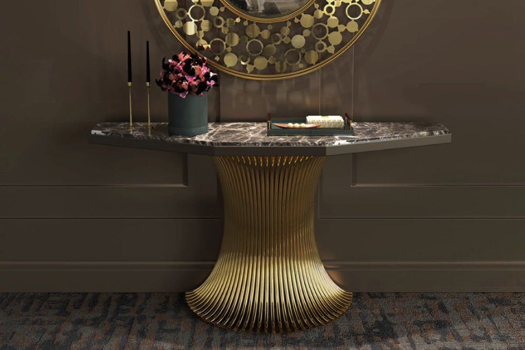Decorative console table with marble top and gold base against a dark wall.
