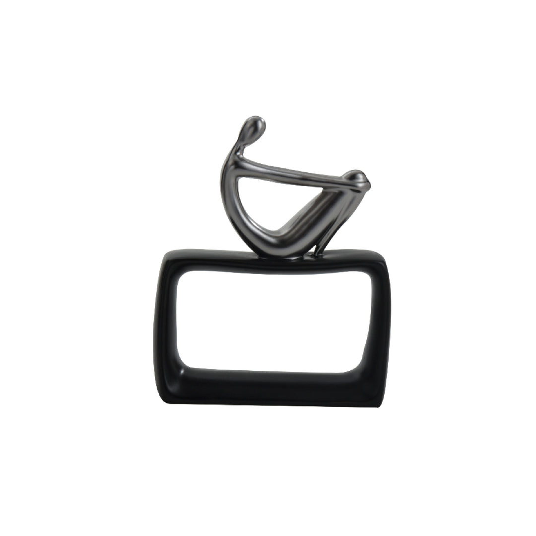 A glossy black ceramic table centerpiece featuring an abstract thinking man figurine sitting on a black rectangular base.