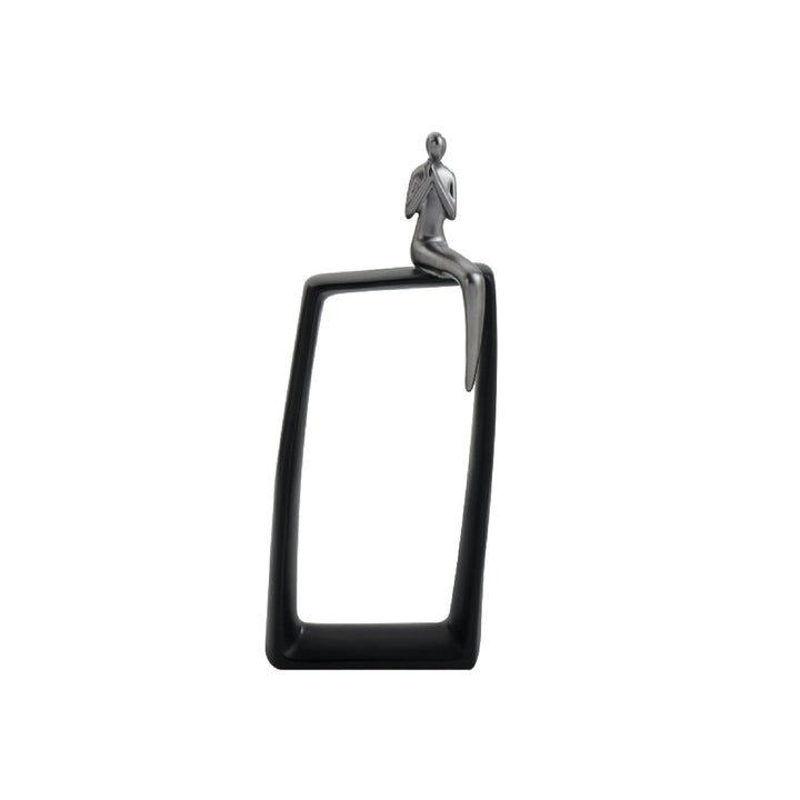 A black ceramic table centerpiece featuring a glossy silver figurine of a man sitting on a hollow rectangular base.