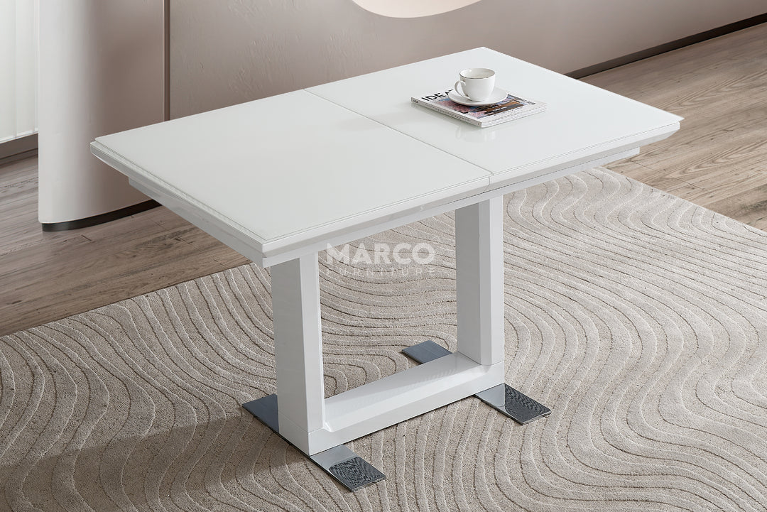 White extendable dining table on a textured floor.