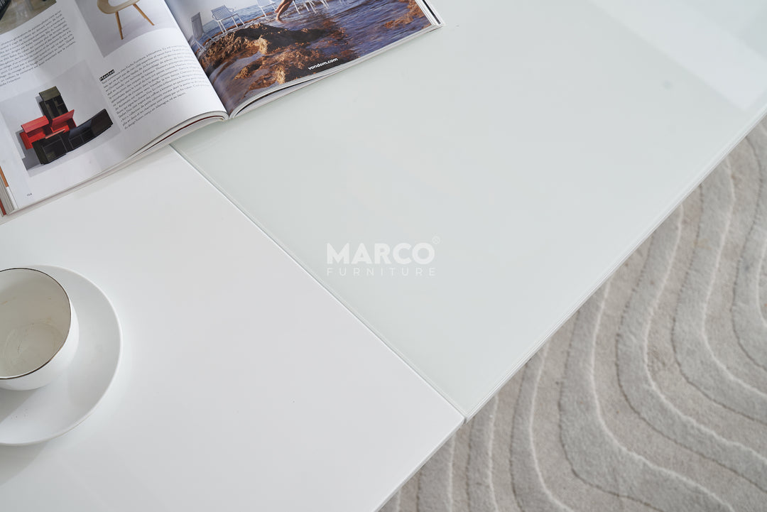 White table with a magazine and cup next to a sand art piece.