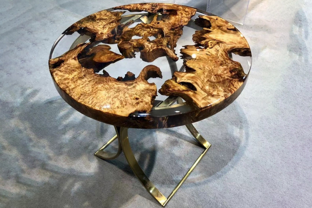 A round Live Edge Epoxy Resin Coffee Table with blue resin and gold-finished metal legs on a patterned floor.