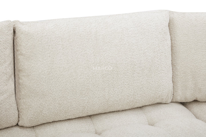 Close-up of a beige sofa with textured fabric and buttoned details.