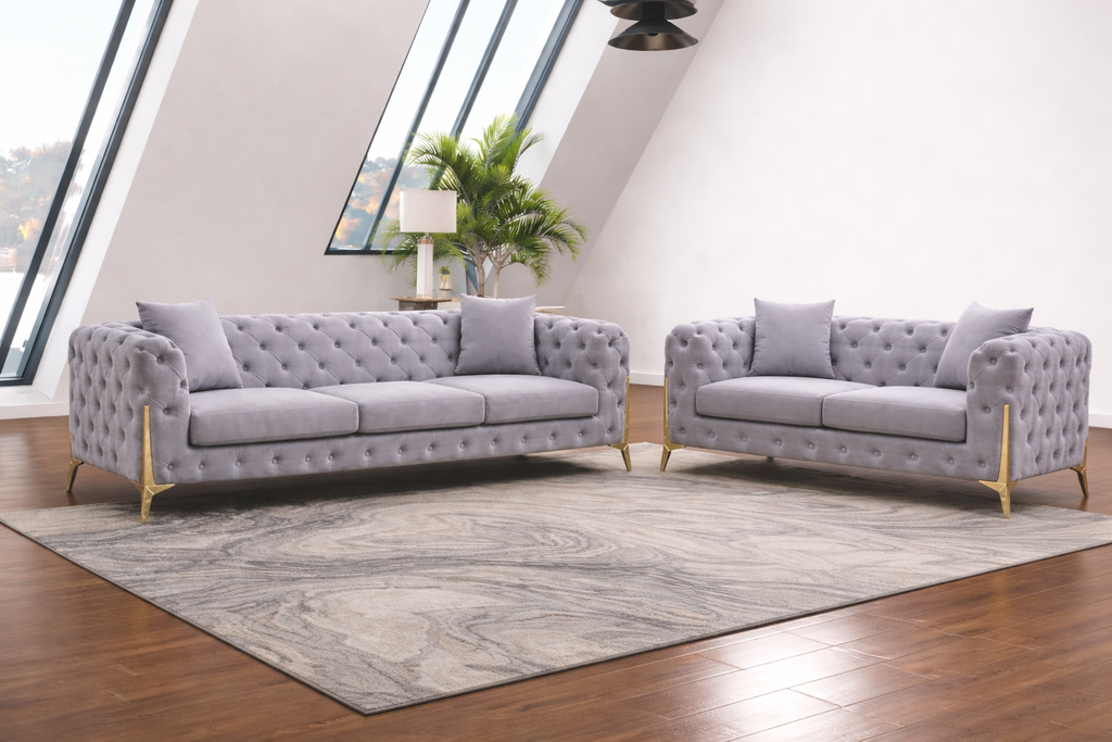 Gray tufted sofa set in a modern living room with large windows.