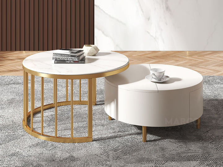 A round modern coffee table with a white high-gloss finish and gold legs, paired with a matching side table that has a marble top and a ribbed gold cage-style base.