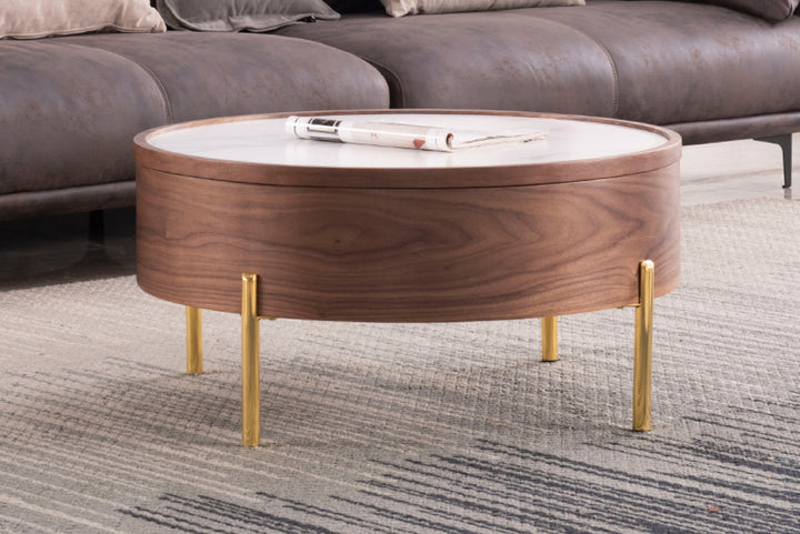 Round wooden coffee table with gold legs in a living room setting.