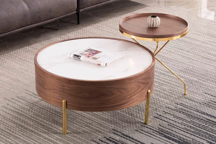 Round wooden coffee table with white top and gold legs in a living room.