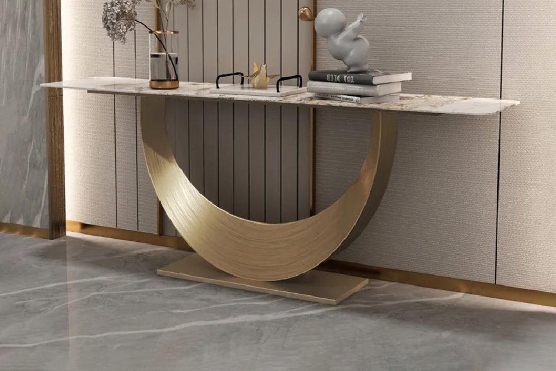 Modern console table with marble surface and gold base against a neutral wall.
