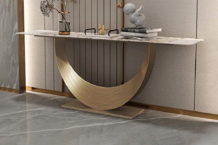 Modern console table with marble surface and gold base against a neutral wall.