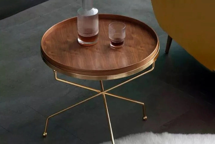 Wooden side table with gold legs on a dark floor