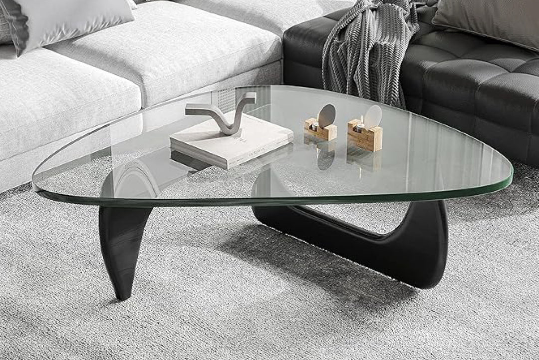 Glass coffee table with black legs in a living room setting.