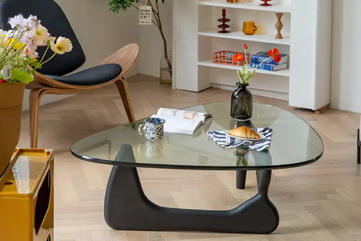 Glass coffee table in a living room setting with decorative items.