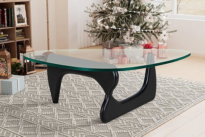 Glass coffee table with black legs in a living room setting.