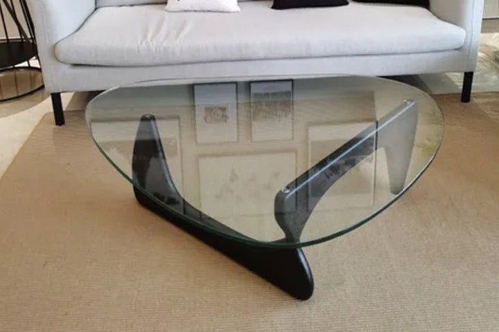 Glass coffee table with black metal base in a living room.