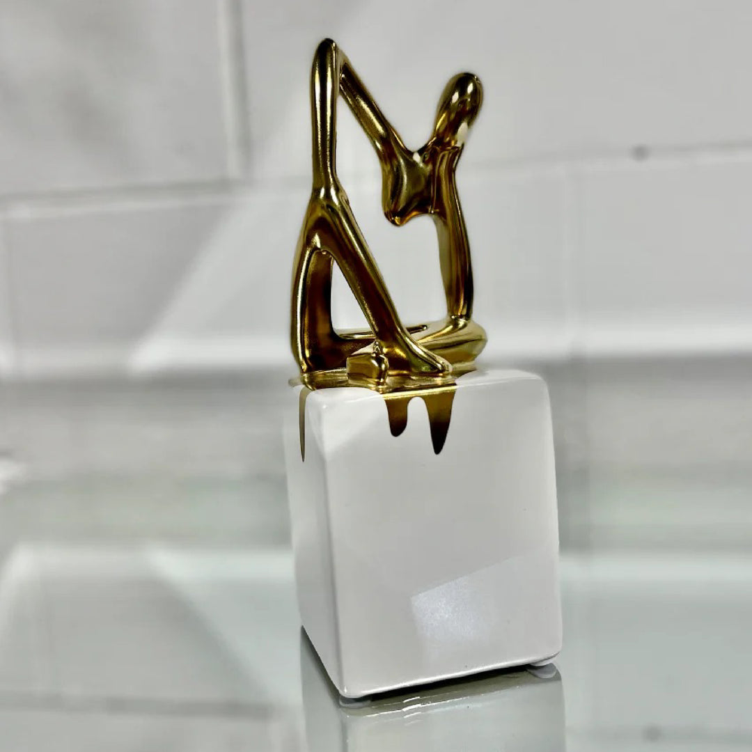 Decorative object with gold figure on a white base against a neutral background