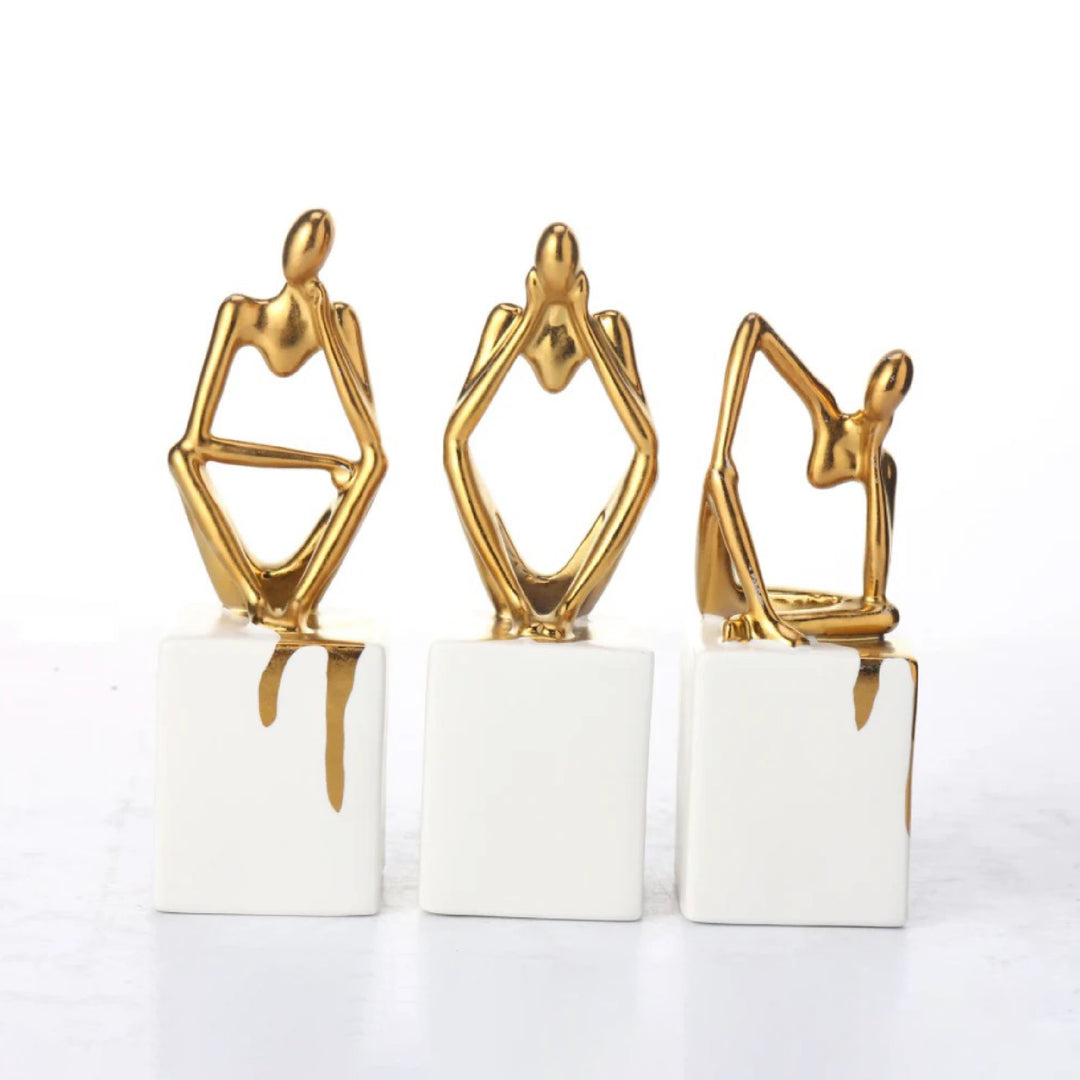 Three gold and white abstract sculptures on a white background