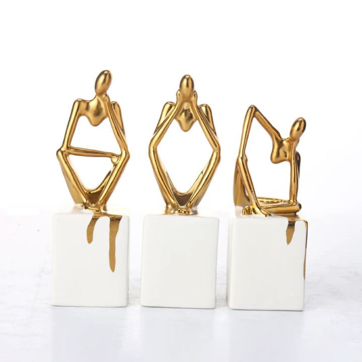 Three gold and white abstract sculptures on a white background