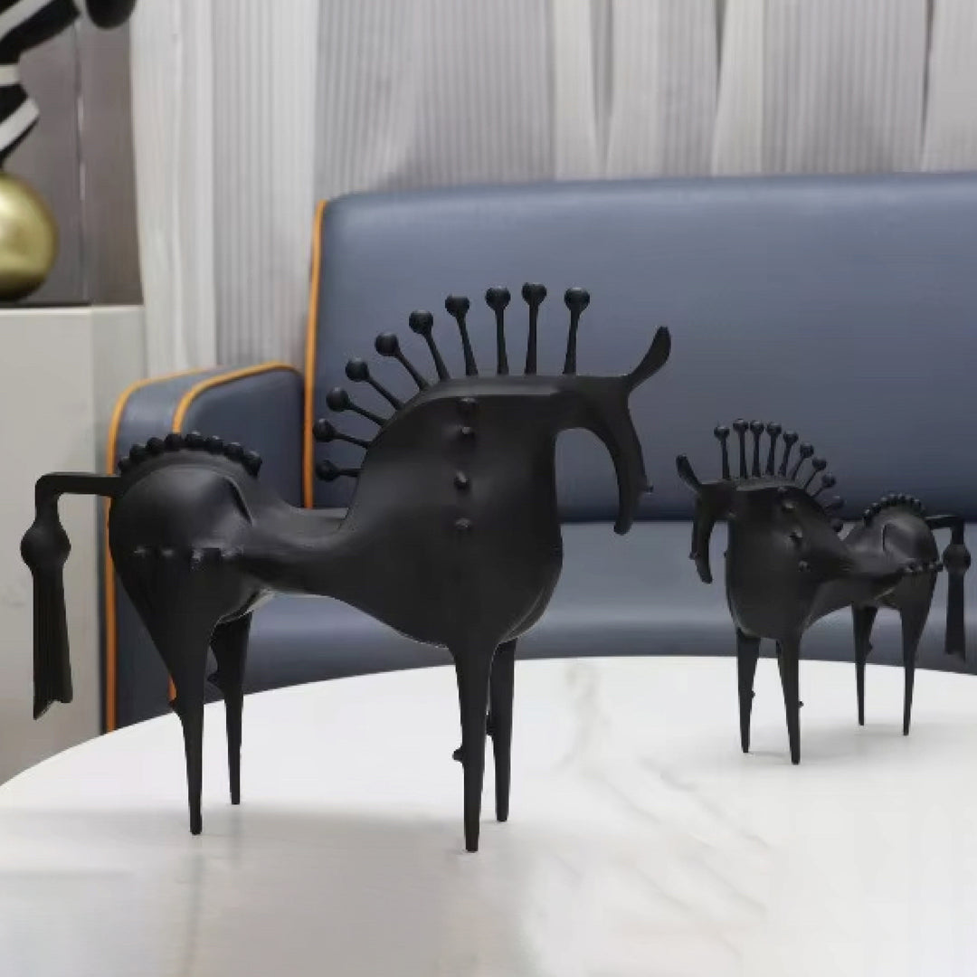 Black horse sculptures on a white surface with a blue sofa in the background