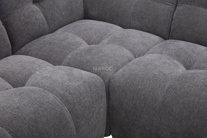 Gray fabric sectional sofa with tufted cushions, brand 'Marco' visible.