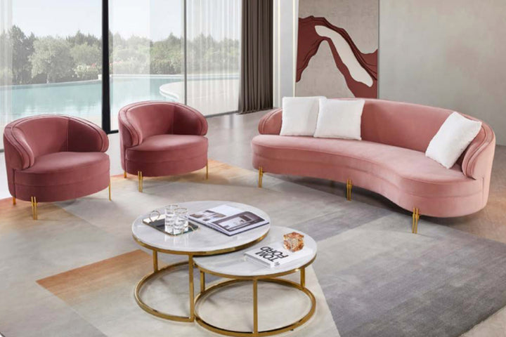 Modern living room with pink sofa and armchairs, marble coffee table, and large windows.