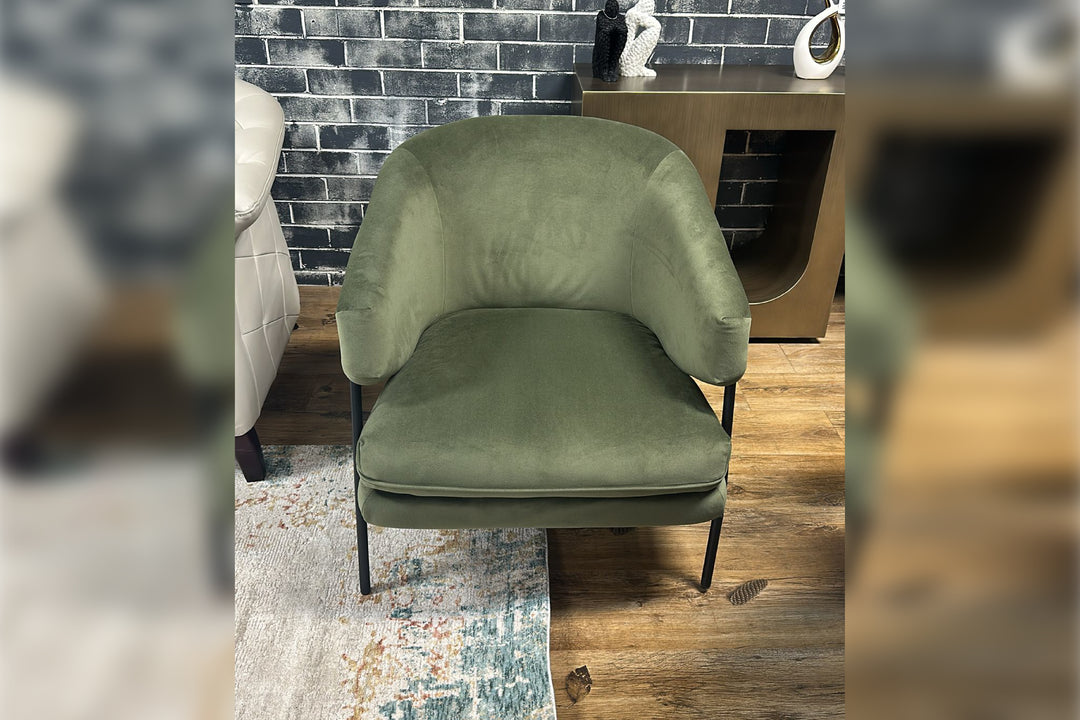 Green chair in a room with a brick wall and wooden floor.