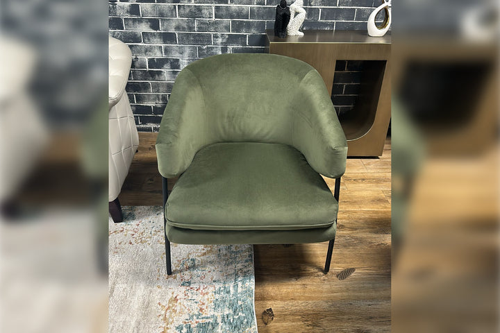 Green chair in a room with a brick wall and wooden floor.