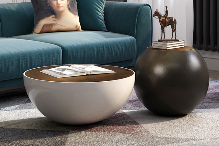 Two round coffee tables with one featuring an open book and the other with a decorative statue, placed on a patterned rug.