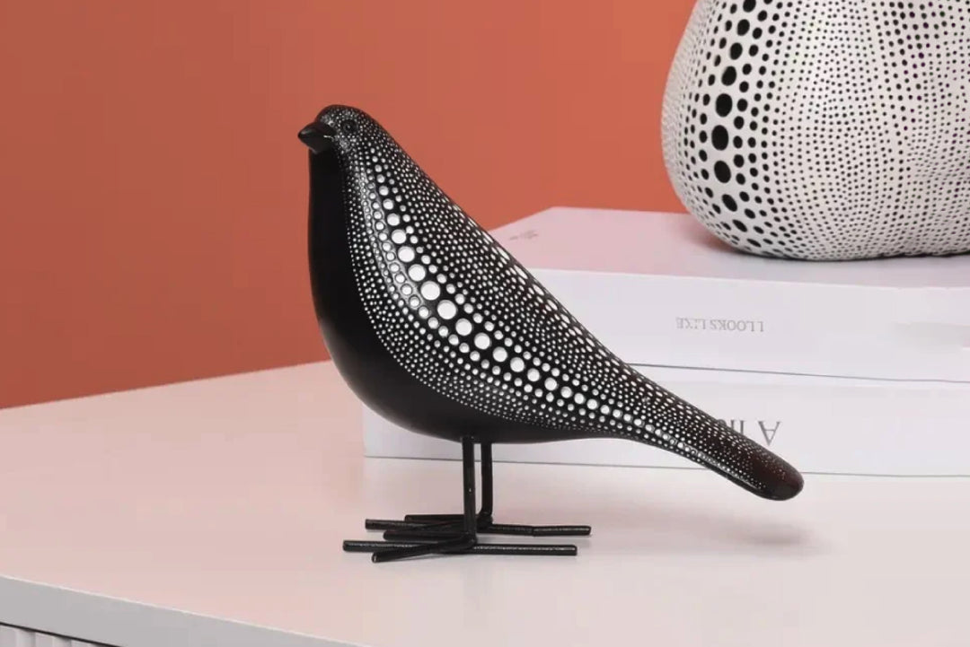 Black and white patterned bird sculpture on a stand with a pink background