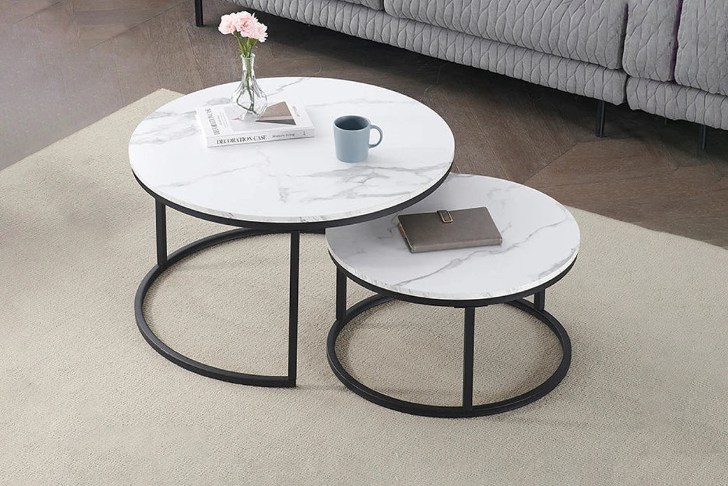 Two nesting coffee tables with a white sintered stone top and black metal base, one larger than the other, placed on a beige carpet.