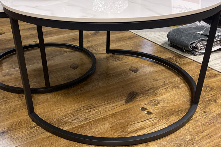 Round coffee table with marble top and black metal frame on a wooden floor.
