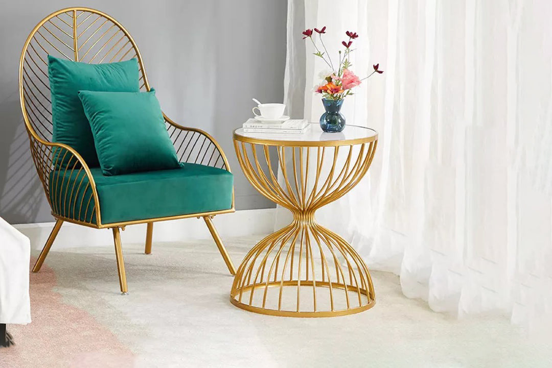 Teal chair with gold frame and matching side table in a room with white curtains.