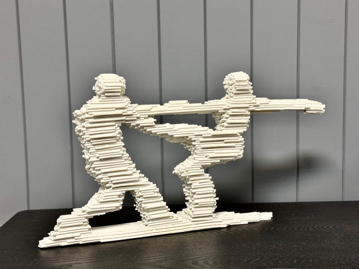 A sculpture of two abstract figures made from high-quality sandstone, depicting a dynamic skating design, placed on a flat surface.