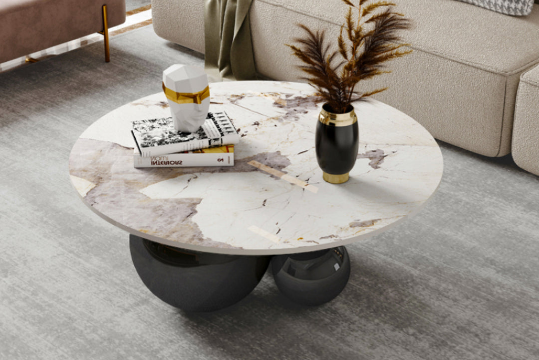 Round marble coffee table in a living room with books and vase.