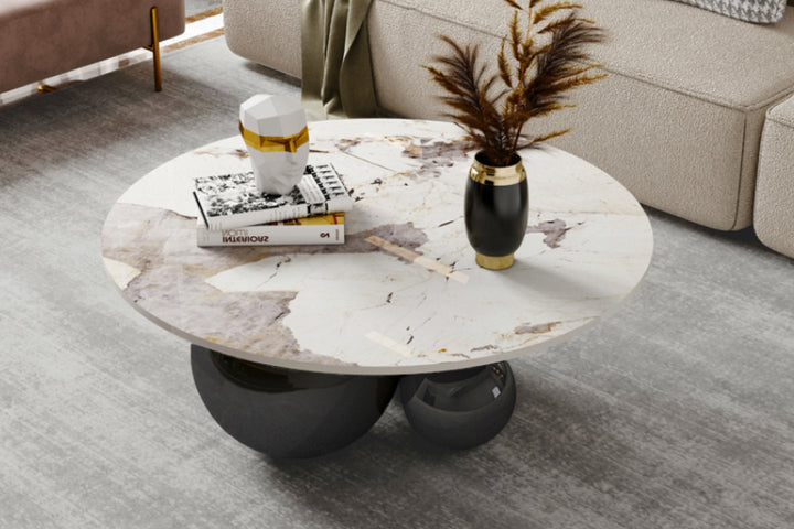 Round marble coffee table in a living room with books and vase.