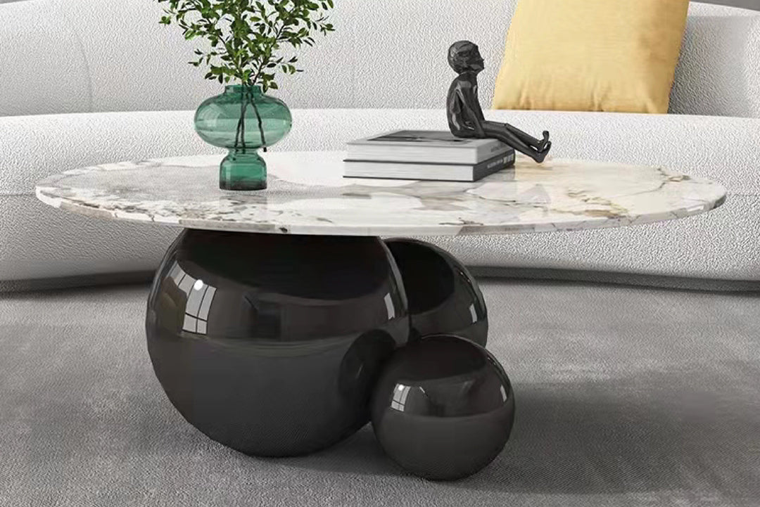 Modern coffee table with marble top and black spherical base in a living room.