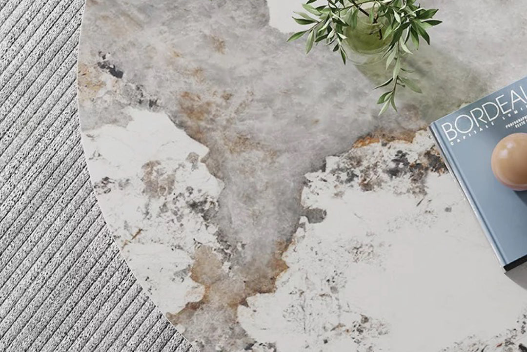 Round marble coffee table with a textured surface, featuring a book and plant.