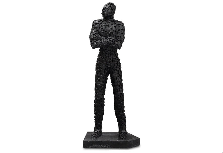 A black brickman figurine standing with arms crossed, made of sandstone with a mosaic texture.