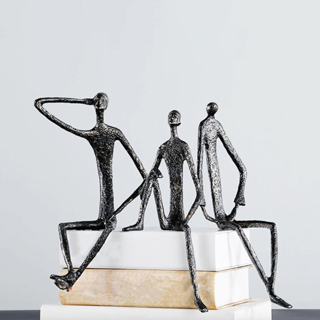 Abstract sculpture of three figures on a white surface with a light gray background