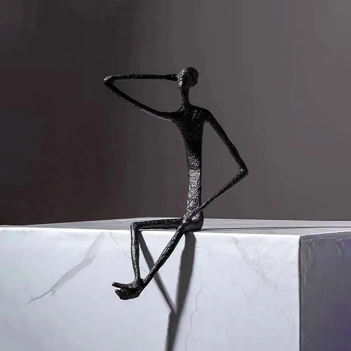 Black abstract sculpture of a figure on a white surface with a dark background