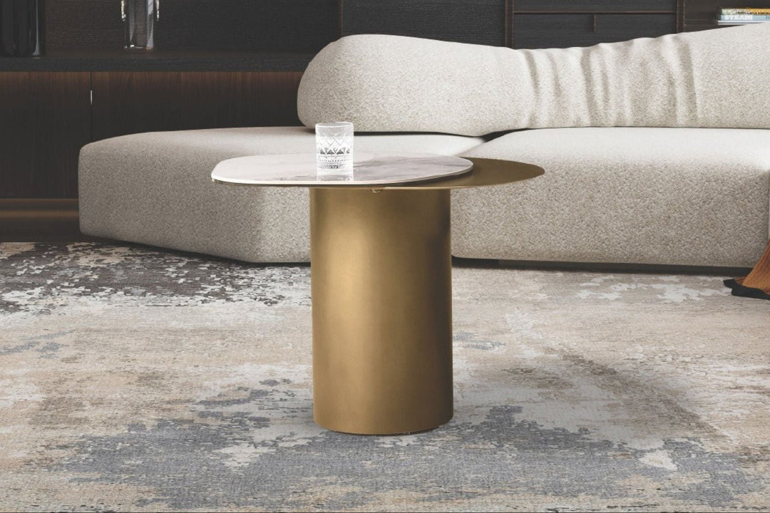 Modern living room with a white sofa, gold coffee table, and abstract rug.