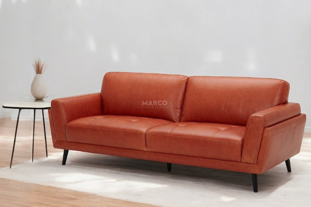 Orange sofa with 'Marco' branding in a minimalistic room.