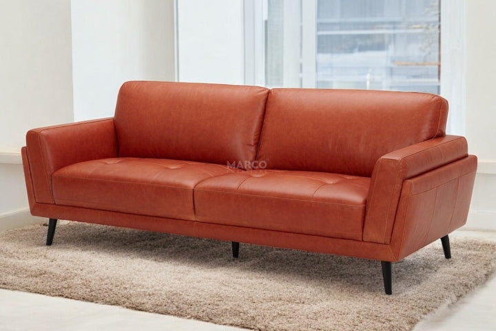 Red leather sofa on a beige rug with a blurred background